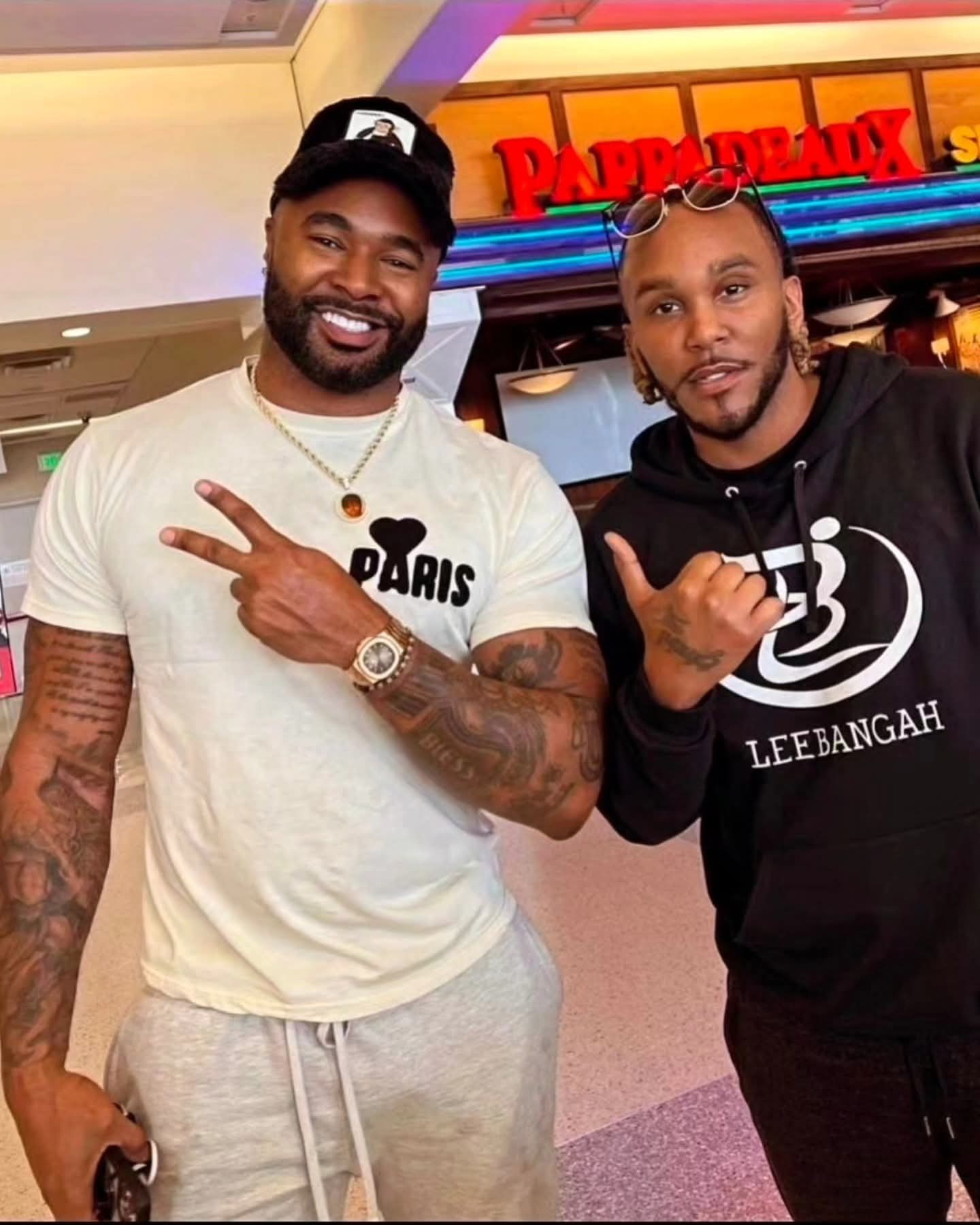 Two men posing, one in a white Paris shirt and one in a black hoodie.